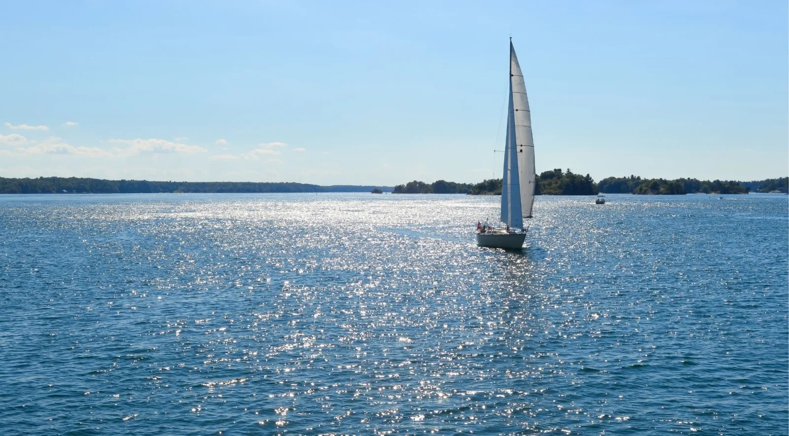 Sailboat crossing the sun-sparkled St. Lawrence River near the Thousand Islands