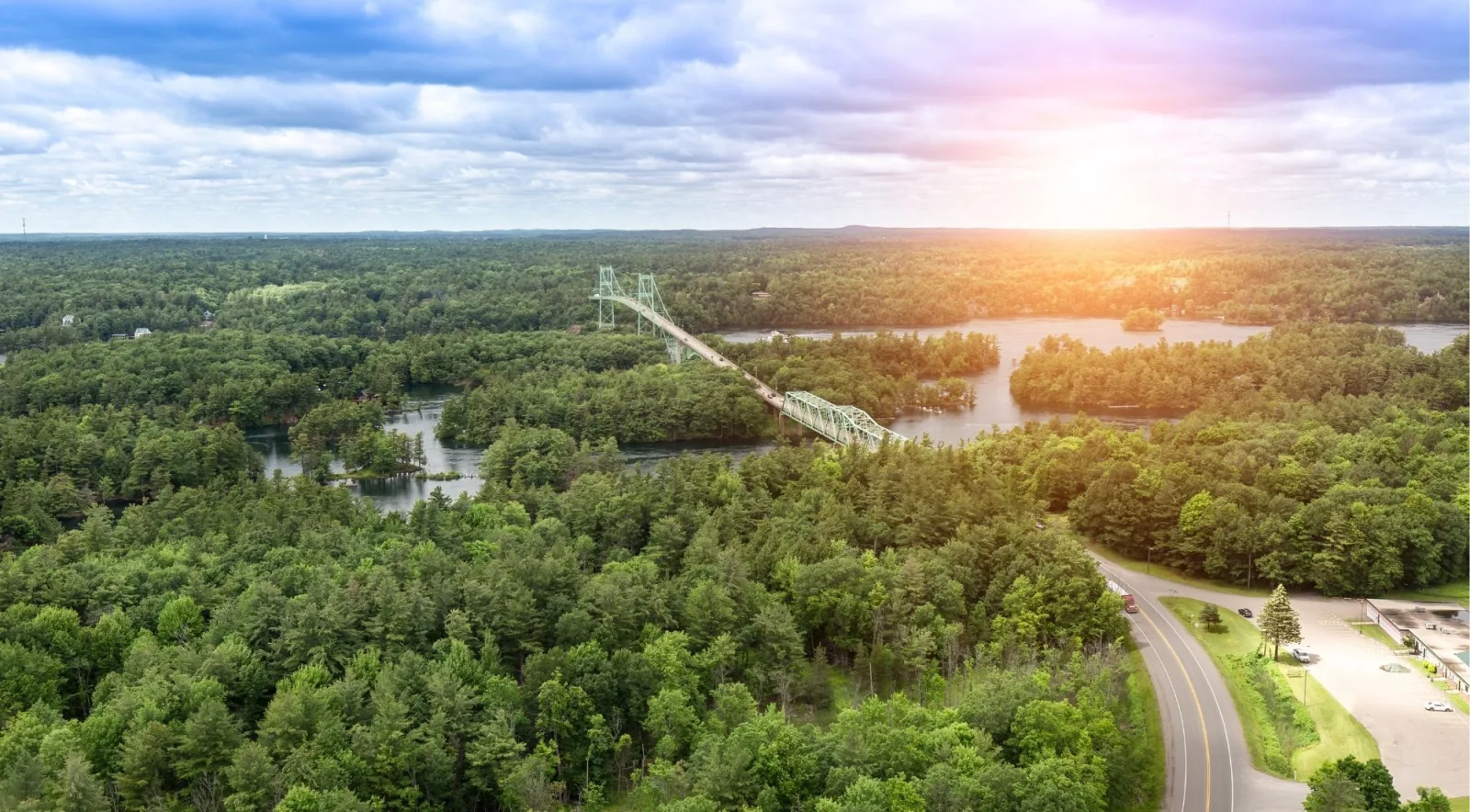 Aerial view of the Thousand Islands International Bridge at sunrise, surrounded by forested islands