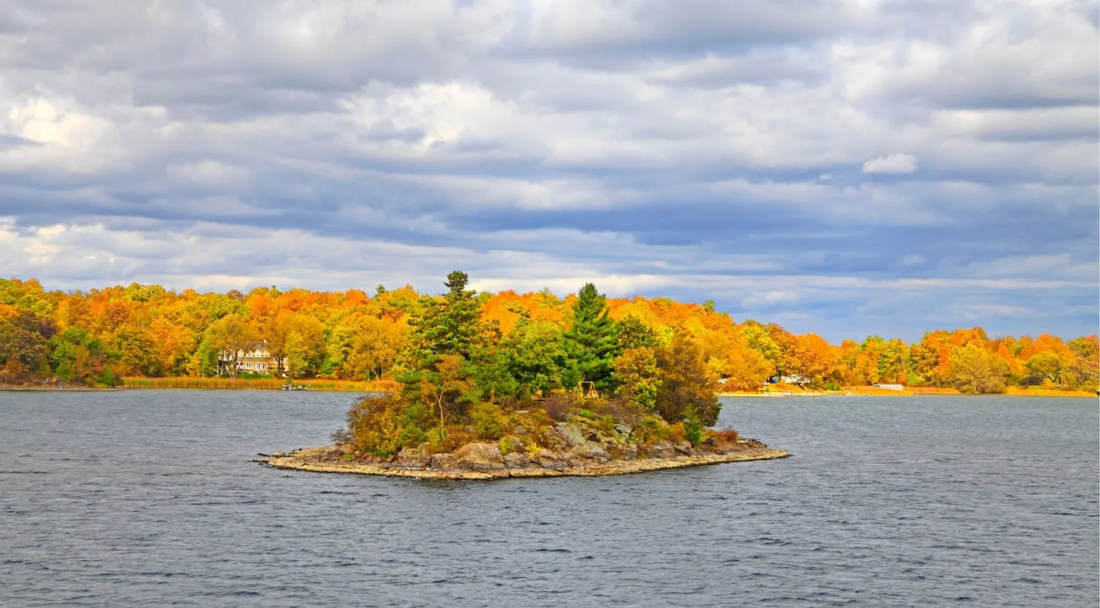 Island covered in orange and gold fall foliage on the St. Lawrence River