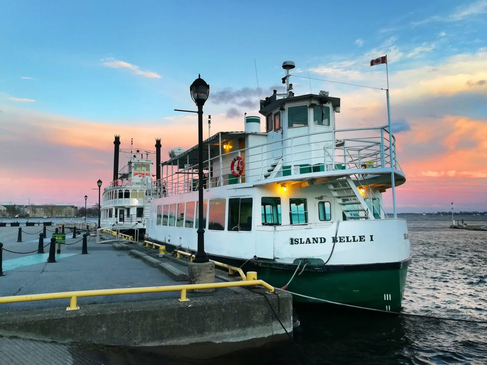 The Island Belle I moored at Crawford Wharf in Kingston under a pink and blue sunset sky, with the Island Queen paddlewheeler tied up behind her
